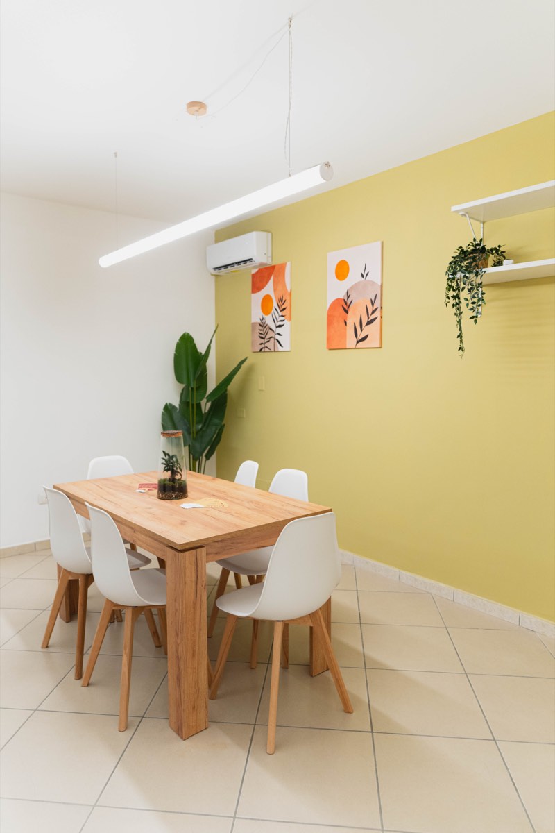 Il tavolo da sei posti nella sala dalla parete verde</picture>